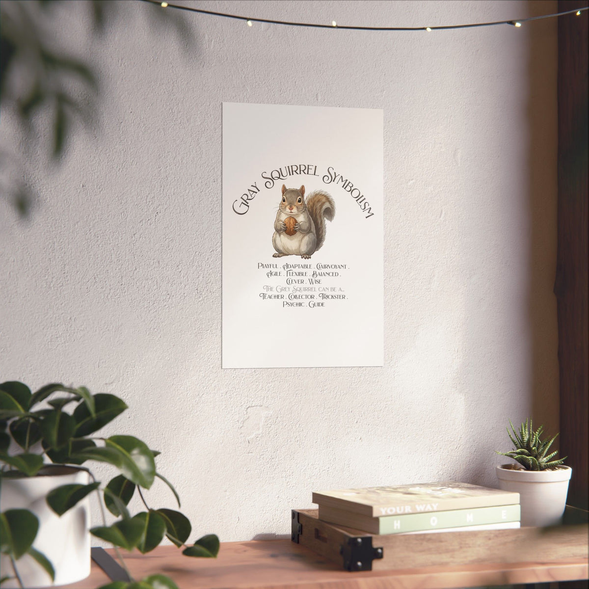 A vertical wall art print featuring a watercolor gray squirrel holding a walnut with the text 'Gray Squirrel Symbolism' and a list of traits, displayed on a light wall above a wooden console table with plants.