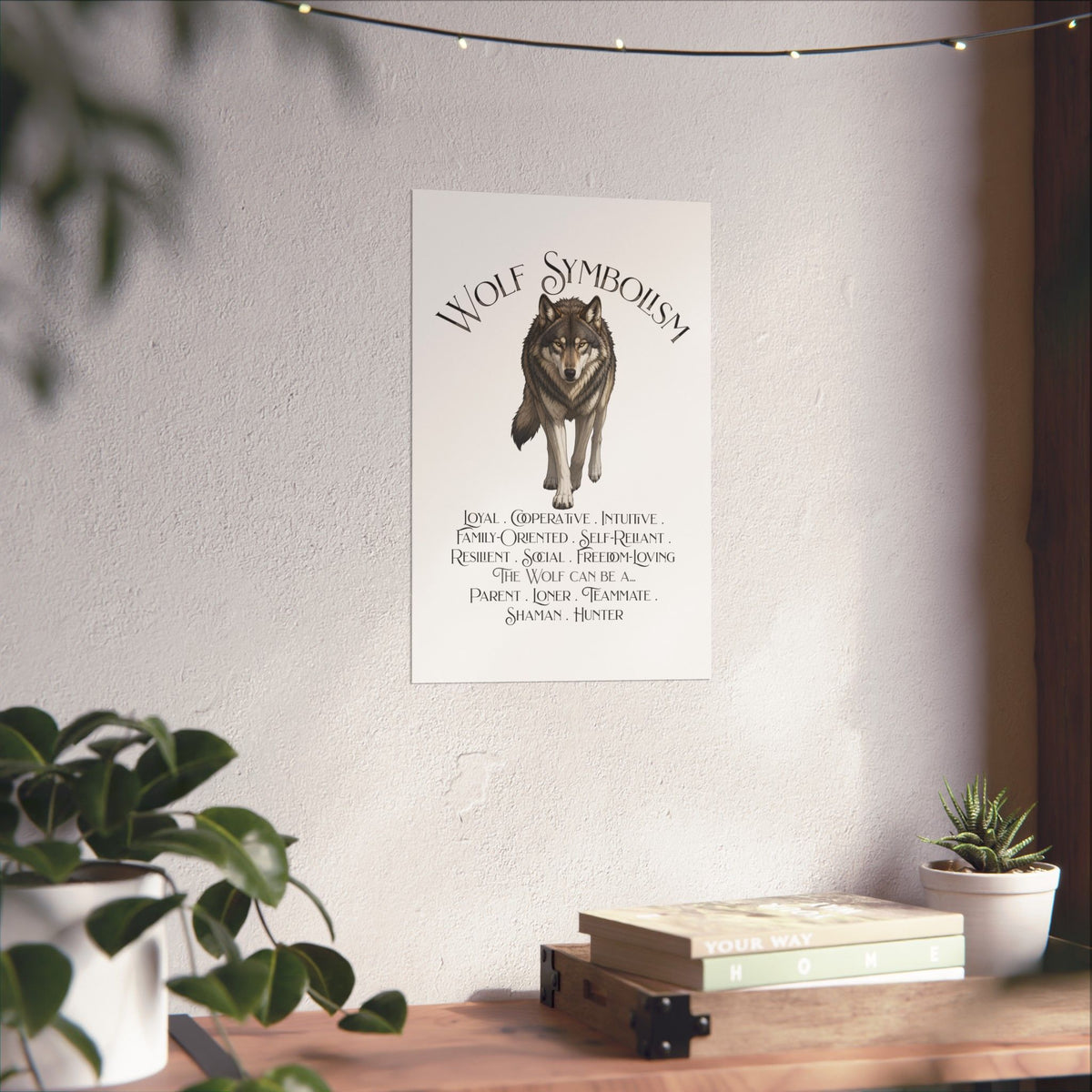 A vertical wall art print featuring a wolf illustration and the text 'WOLF SYMBOLISM' with traits and roles listed below, displayed on a light wall in a styled interior with plants and a wooden shelf.