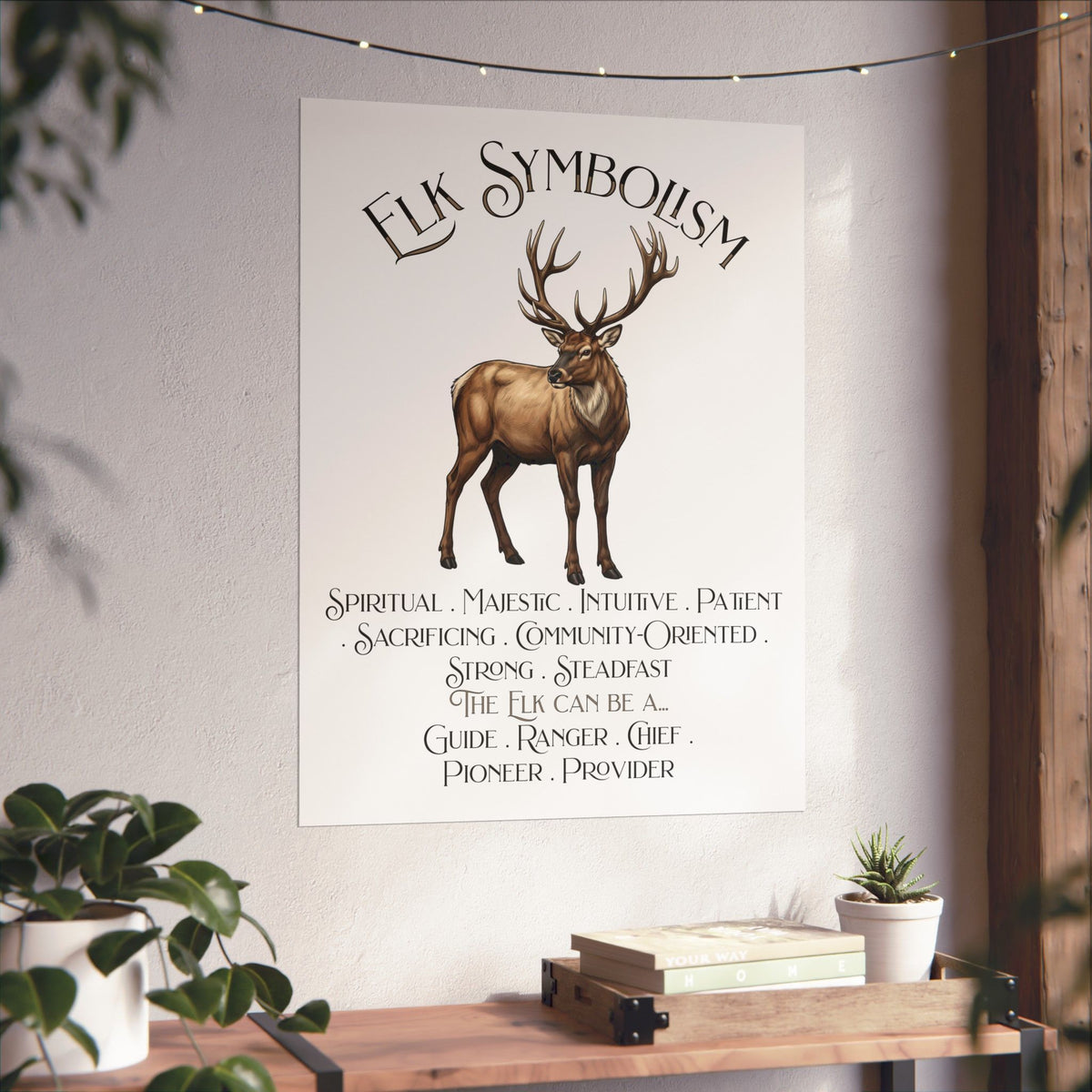 A vertical wall art print featuring a brown elk illustration and the title 'Elk Symbolism' with text listing its meanings. The print is displayed on a light wall above a wooden shelf with books and small plants.