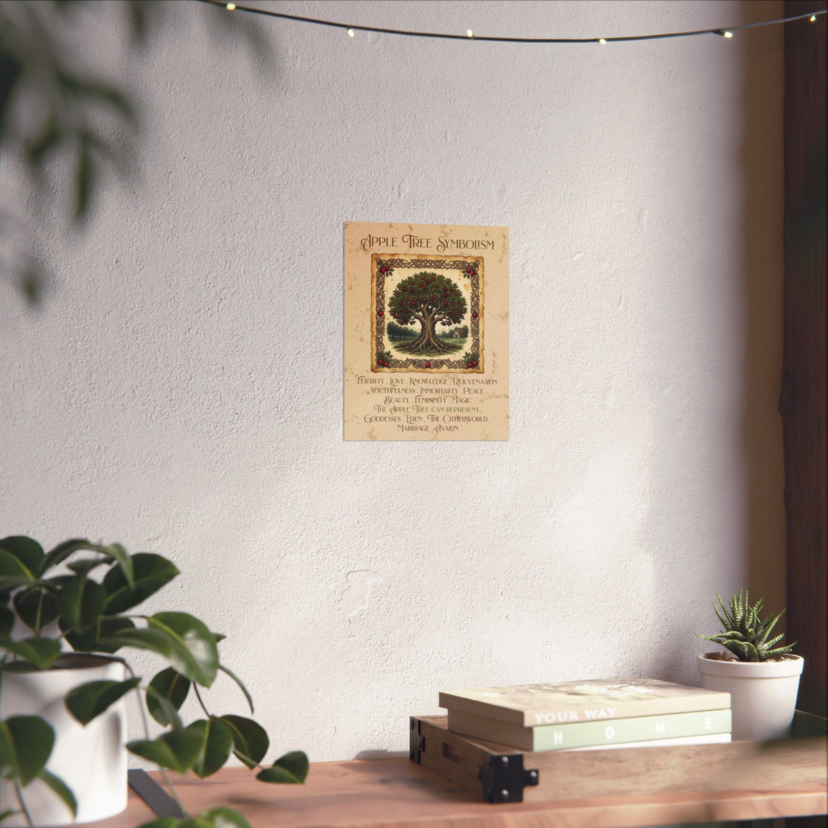 A vertical wall art print titled 'Apple Tree Symbolism' hanging on a light wall above a wooden shelf with books and small plants. The print shows an illustrated apple tree with red apples and decorative text below, styled in a cozy indoor setting with string lights and plant leaves framing the scene.