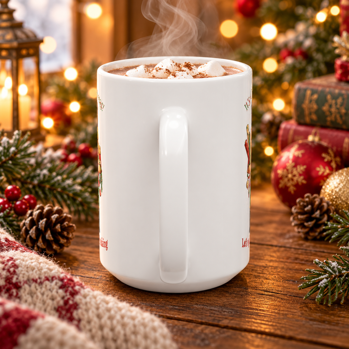 A white ceramic mug filled with hot cocoa and topped with marshmallows and cocoa powder, set on a wooden table surrounded by Christmas decorations including pine branches, ornaments, a lantern, and wrapped gifts.