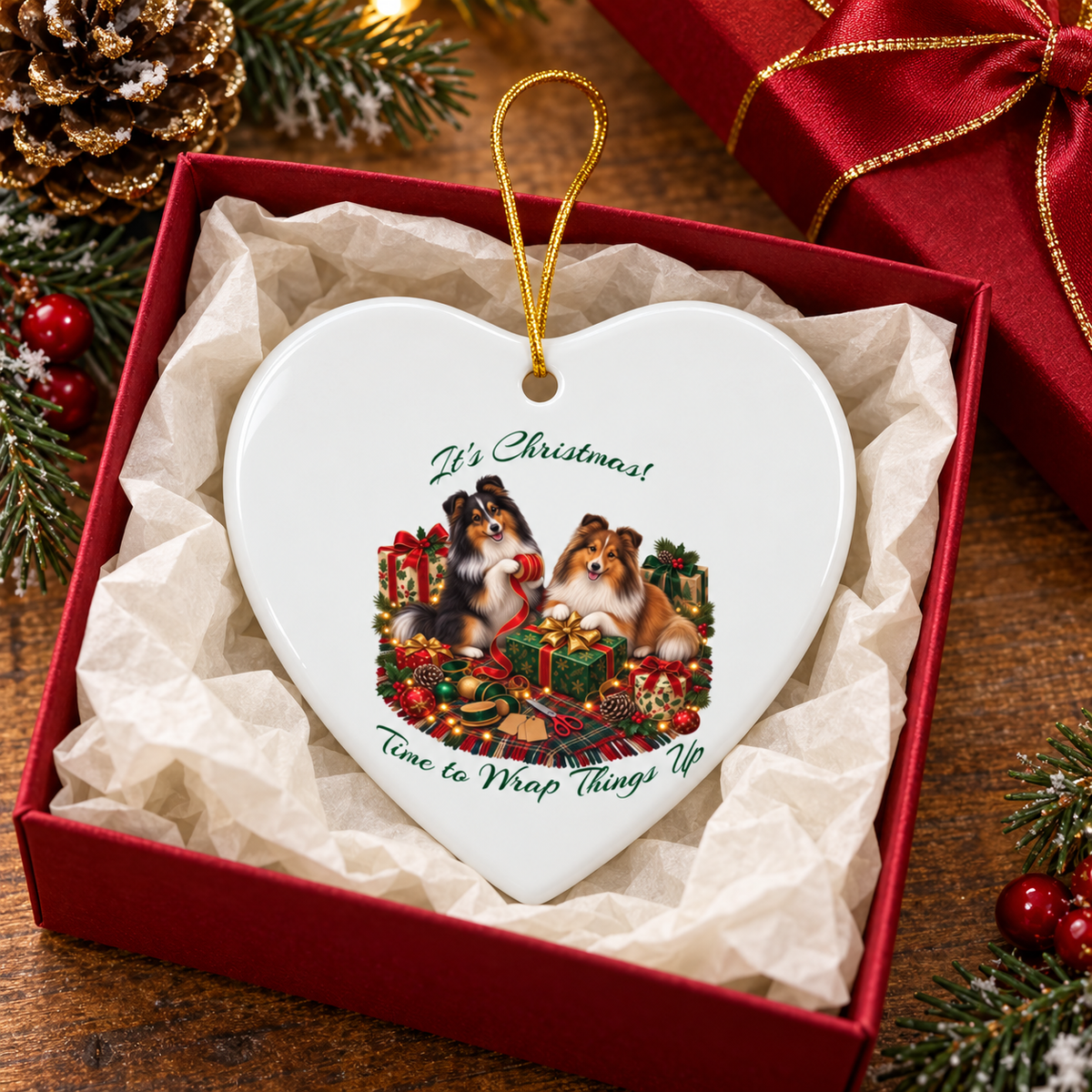 Heart-shaped Christmas ornament in a red gift box with tissue paper. The ornament features two shelties and the text 'It's Christmas! Time to Wrap Things Up' and has a gold hanging loop.