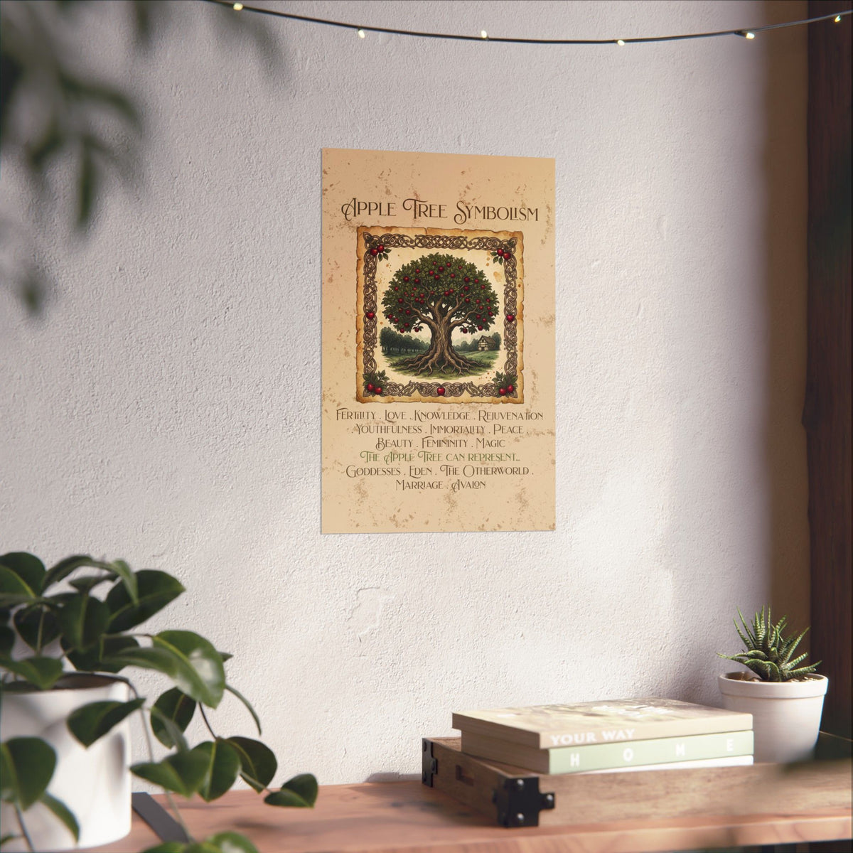 A vertical wall art print titled 'Apple Tree Symbolism' hanging on a light wall above a wooden shelf with books and small plants. The print shows an illustrated apple tree with red apples and decorative text below, styled in a cozy indoor setting with string lights and plant leaves framing the scene.