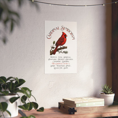 A vertical wall art print featuring a red cardinal on a pine branch with the title 'Cardinal Symbolism' and a list of cardinal qualities and meanings, displayed on a light wall above a wooden shelf with books and plants.
