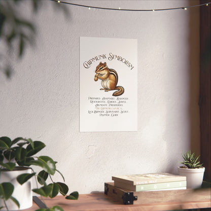 A vertical white art print featuring a chipmunk and the title 'Chipmunk Symbaristy' with smaller text below, hanging on a textured wall in a styled room with plants, books, and string lights.