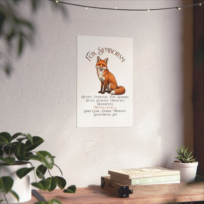 A vertical wall art print featuring an illustrated red fox and the text 'Fox Symbolism' displayed on a textured white wall above a wooden shelf with books and small plants.