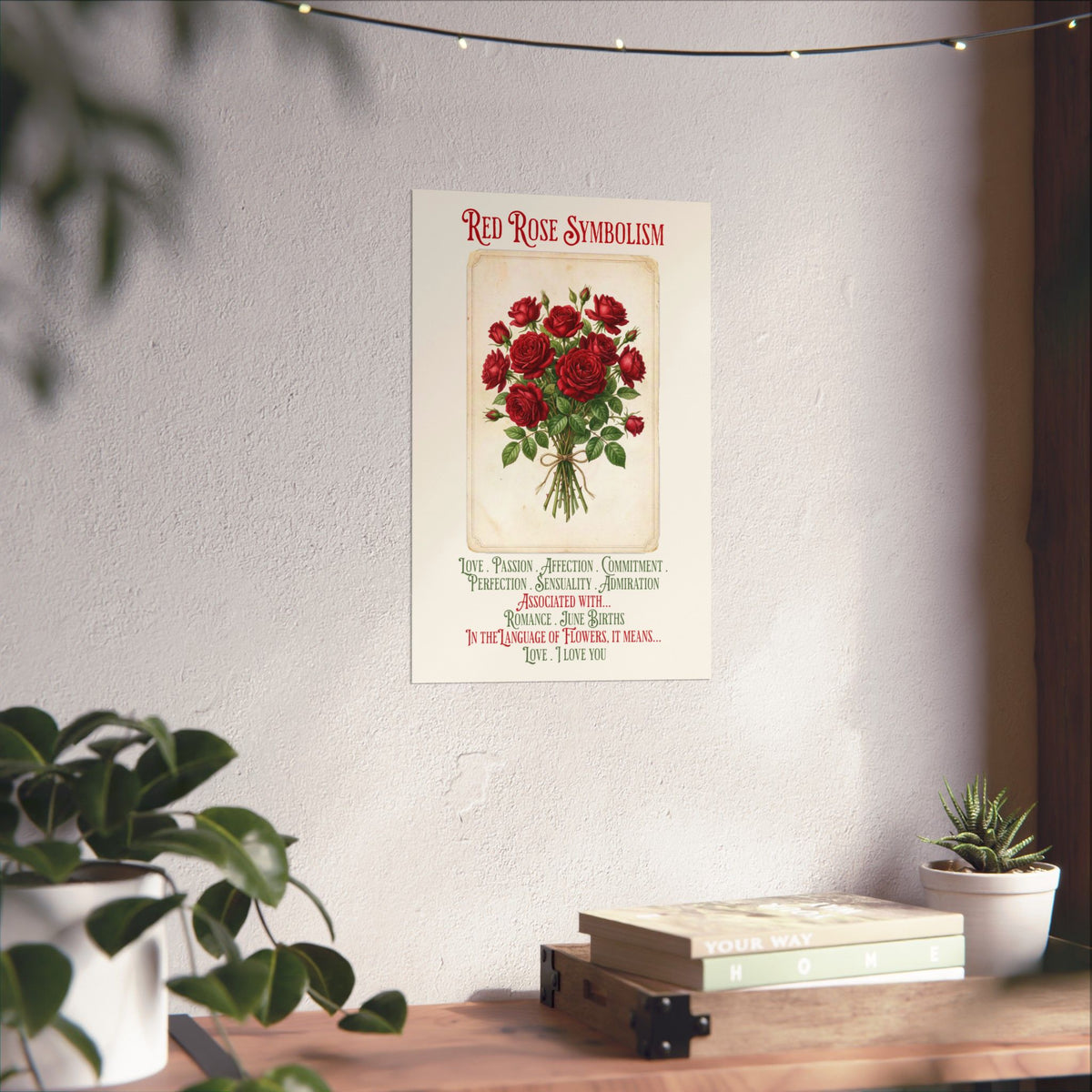 A vintage-style wall art print titled 'Red Rose Symbolism' featuring a bouquet of red roses, hanging on a textured white wall above a wooden shelf with books and small potted plants.