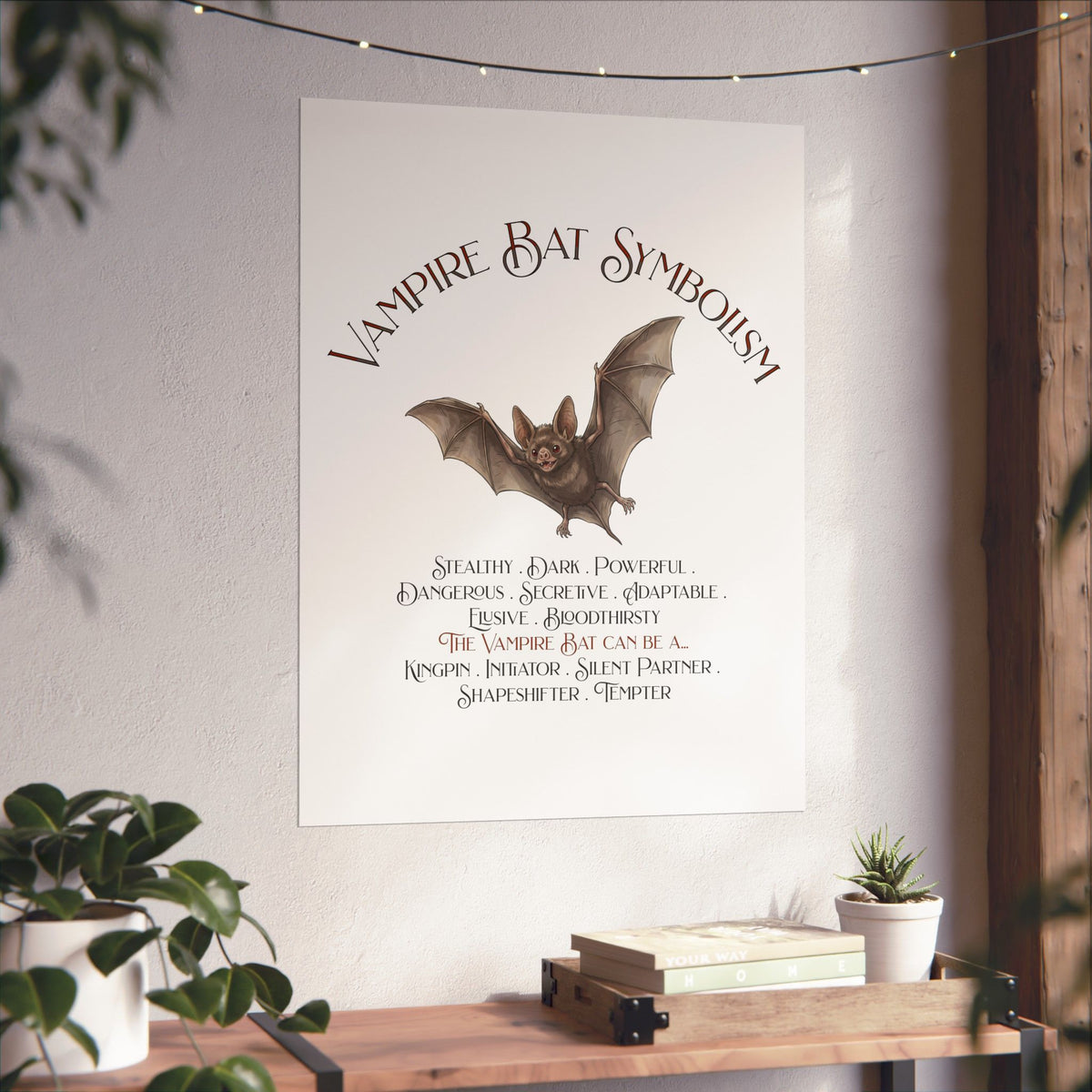 A vertical wall poster featuring 'Vampire Bat Symbolism' with an illustration of a bat and a list of symbolic qualities, displayed on a wall above a wooden console table with plants.