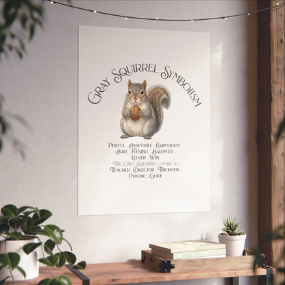 A vertical wall art print featuring a watercolor gray squirrel holding a walnut with the text 'Gray Squirrel Symbolism' and a list of traits, displayed on a light wall above a wooden console table with plants.