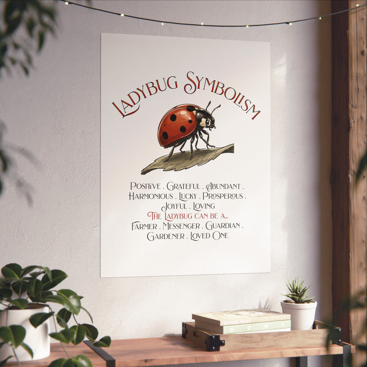 A vertical wall art print featuring a ladybug illustration and the text 'Ladybug Symbolism' with a list of qualities and meanings, displayed on a light wall above a wooden console with plants and books.