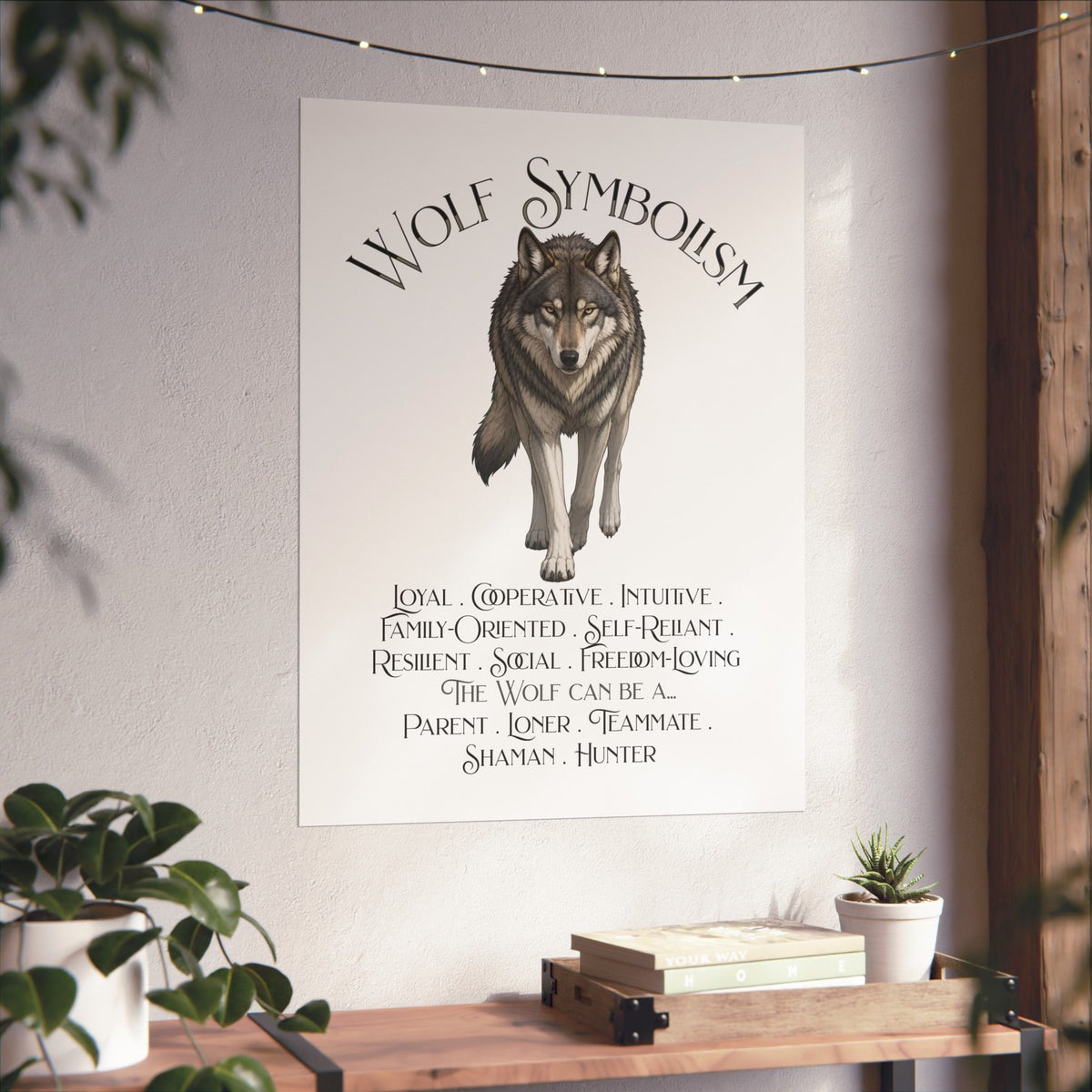 A vertical wall art print featuring a wolf illustration and the text 'WOLF SYMBOLISM' with traits and roles listed below, displayed on a light wall in a styled interior with plants and a wooden shelf.