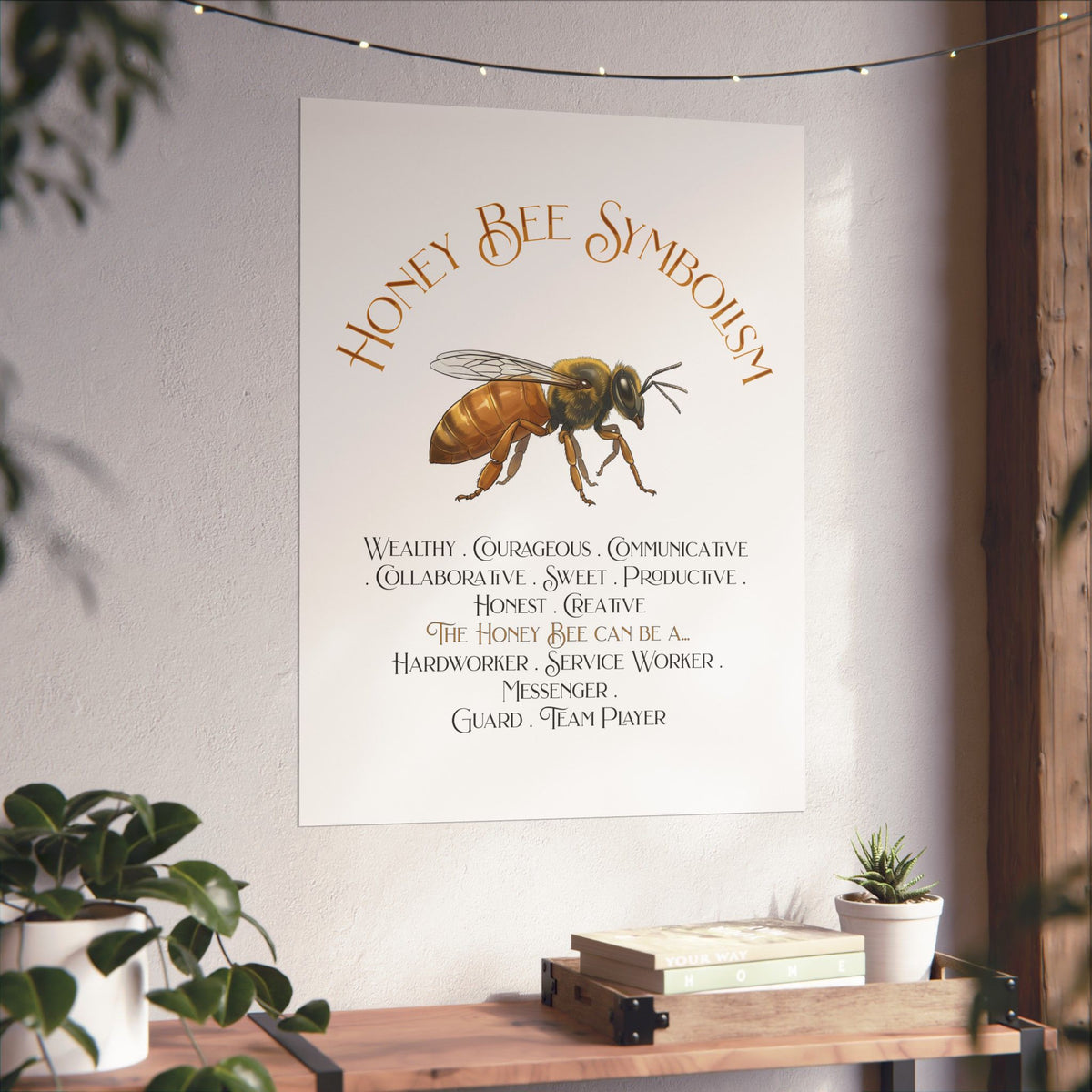 A vertical wall art print featuring a watercolor-style bee and the text 'Honey Bee Symbolism' with a list of qualities and roles, displayed on a light wall above a wooden shelf with plants and books.
