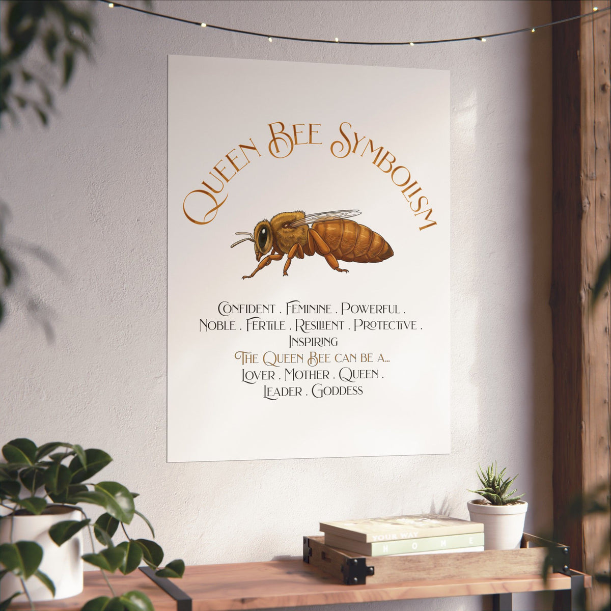 A vertical wall art print featuring a watercolor-style queen bee and the text 'Queen Bee Symbolism' with a list of qualities and roles, displayed on a light wall above a wooden shelf with plants and books.