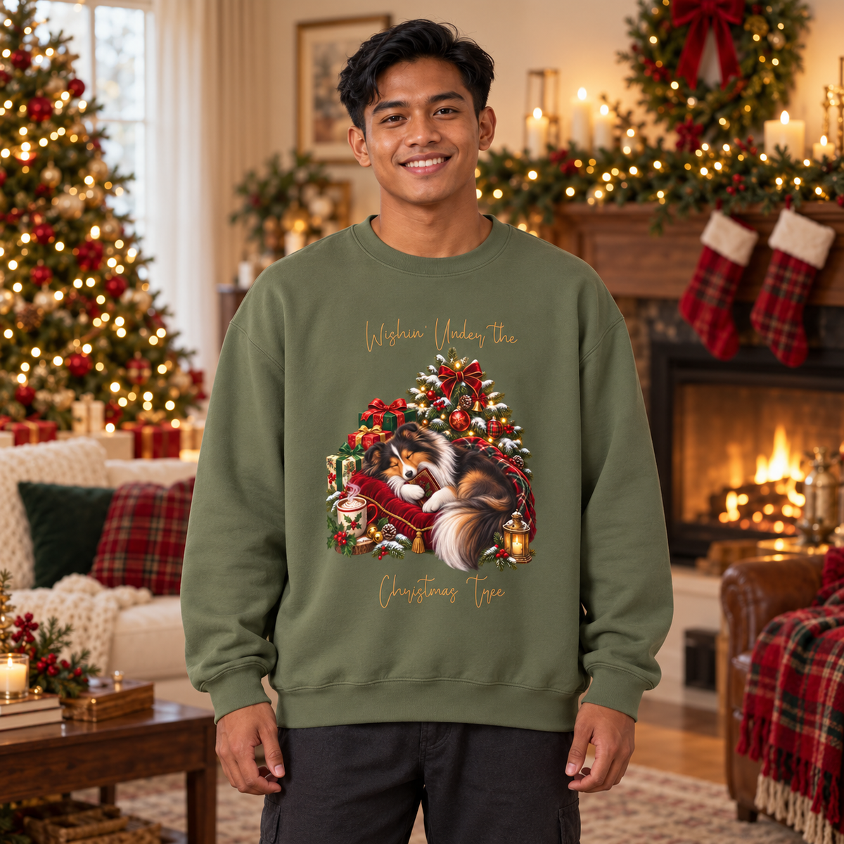 A man wearing an olive green sweatshirt with a festive Christmas graphic of a Shetland sheepdog under a decorated tree. The man stands in a cozy, warmly lit Christmas living room.