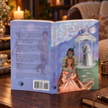 A paperback titled 'Faithful: When Conquers Death' displayed open on a mahogany table, showing both the front and back covers with colorful romantasy illustrations, set against a softly blurred background with a lit candle, teacup, vase of flowers, and a leather chair with a pillow and knit blanket.