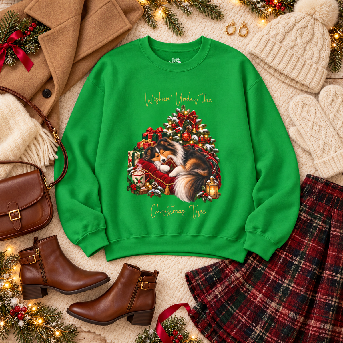 A bright green crewneck sweatshirt with a festive Christmas tree graphic featuring a fluffy dog and the text 'Wishin' Under the Christmas Tree', styled in a cozy flat-lay with brown boots, a plaid skirt, a coat, a handbag, and knit accessories.
