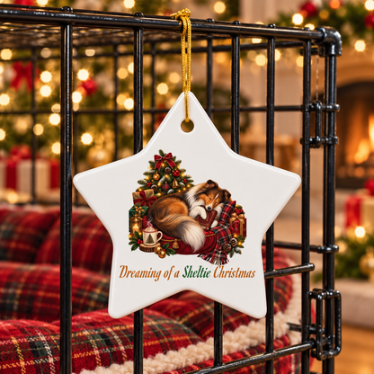 A white star-shaped ceramic Christmas ornament hanging from a black metal pet crate. The ornament features an illustration of a Sheltie, holding a book, curled up on a red bed beside a steaming mug and gifts in front of a decorated Christmas tree.