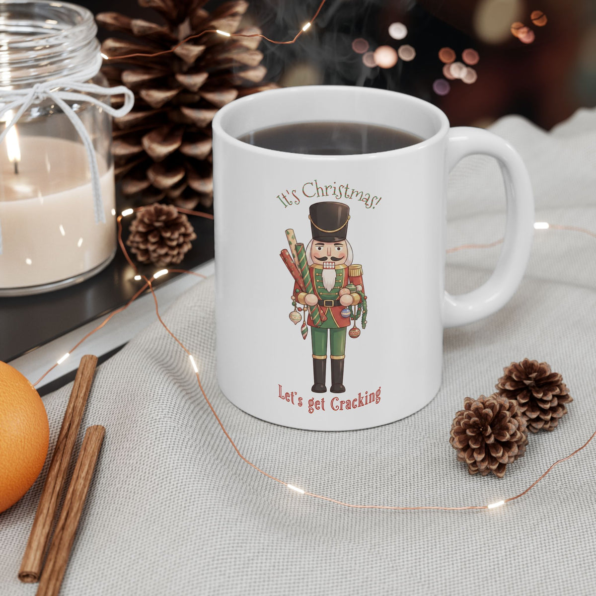 White mug with a nutcracker holding gift wrap and decorations. The surrounding words say, It's Christmas! Let's get cracking.